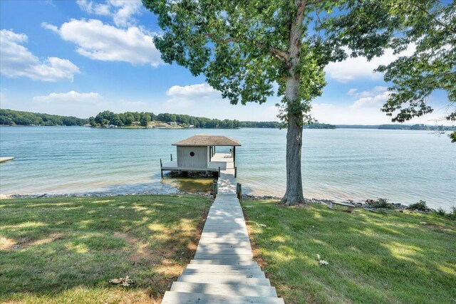 dock area with a lawn and a water view