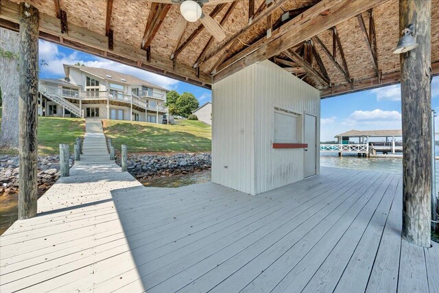 wooden deck with a water view, a dock, and ceiling fan