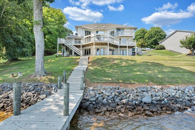 rear view of property with a deck with water view and a yard