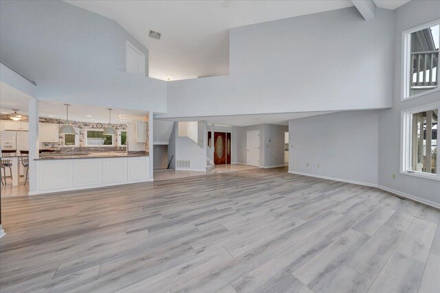 unfurnished living room featuring light wood-type flooring and a high ceiling