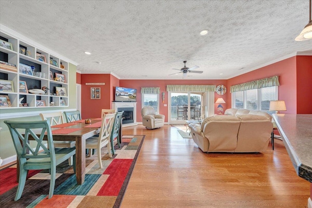 living room with ornamental molding, hardwood / wood-style floors, a textured ceiling, and ceiling fan