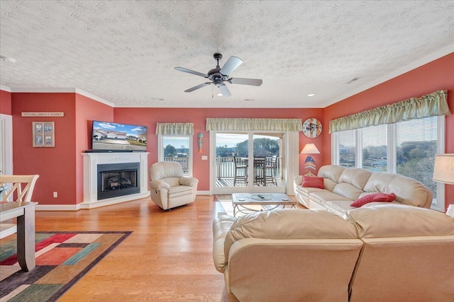 living room featuring hardwood / wood-style flooring, ornamental molding, a textured ceiling, and ceiling fan