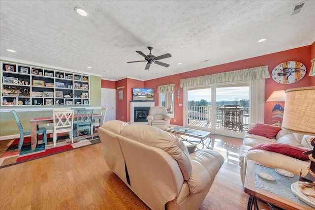 living room with ceiling fan, light hardwood / wood-style flooring, and a textured ceiling