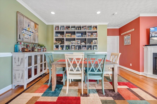 dining space featuring ornamental molding, wood-type flooring, and a textured ceiling