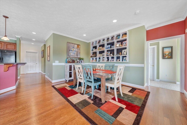 dining area featuring ornamental molding, light hardwood / wood-style floors, and a textured ceiling