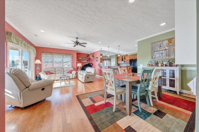 dining room with ornamental molding, ceiling fan, a textured ceiling, and light wood-type flooring