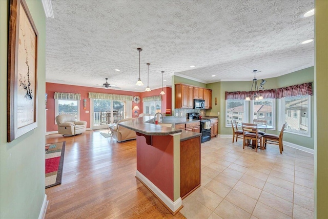 kitchen featuring sink, black appliances, a kitchen bar, decorative light fixtures, and kitchen peninsula