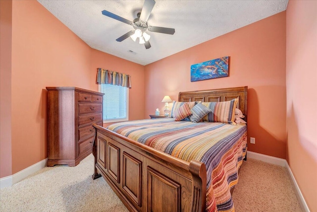 bedroom featuring ceiling fan, light colored carpet, and a textured ceiling