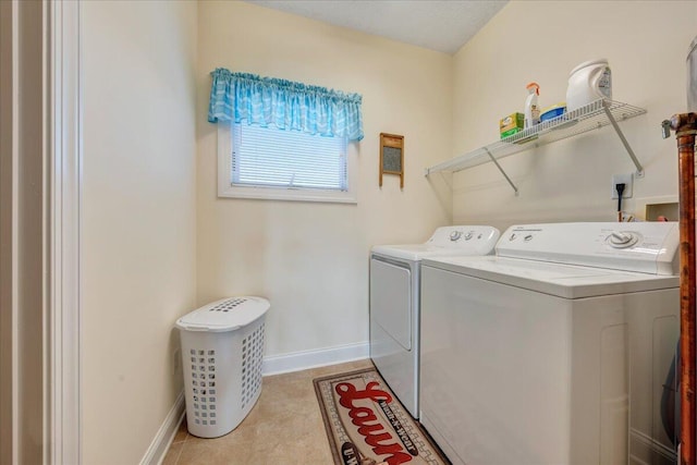 clothes washing area with washing machine and dryer and light tile patterned floors