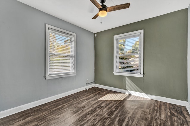 spare room featuring dark wood-type flooring, a wealth of natural light, and ceiling fan