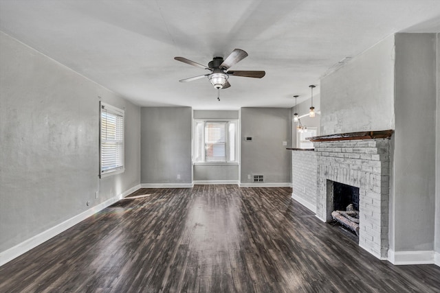 unfurnished living room with a brick fireplace, dark wood-type flooring, and ceiling fan