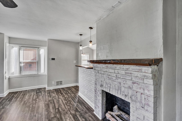 unfurnished living room featuring dark wood-type flooring, lofted ceiling, a healthy amount of sunlight, and a brick fireplace