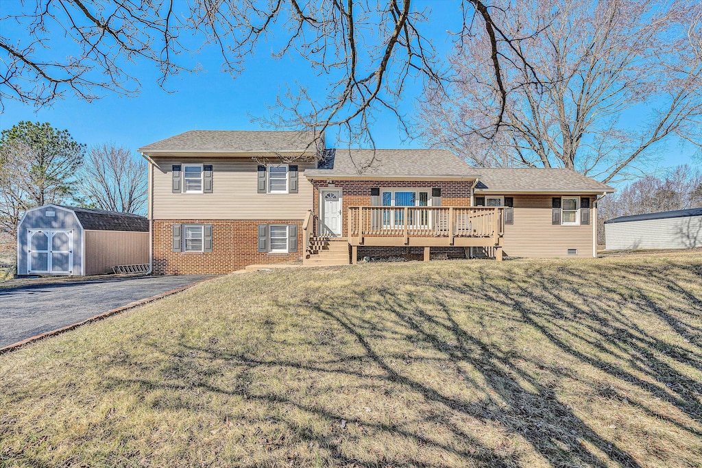 rear view of house featuring a wooden deck, a yard, and a storage shed