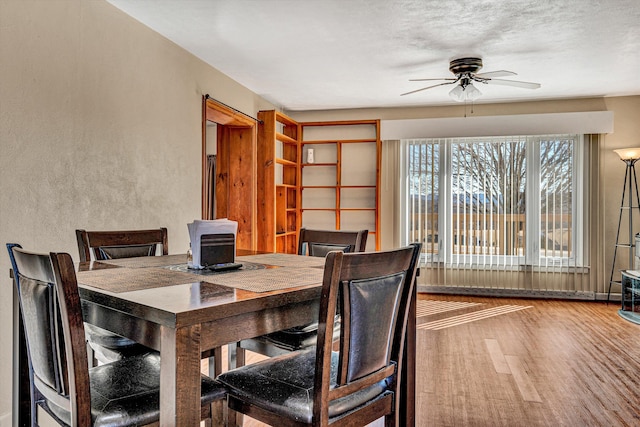 dining space featuring hardwood / wood-style flooring, a textured ceiling, and ceiling fan