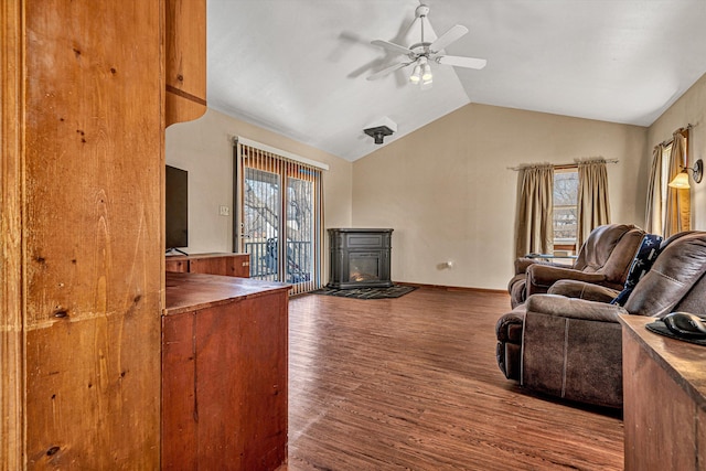 living room with ceiling fan, lofted ceiling, a wood stove, and dark hardwood / wood-style floors