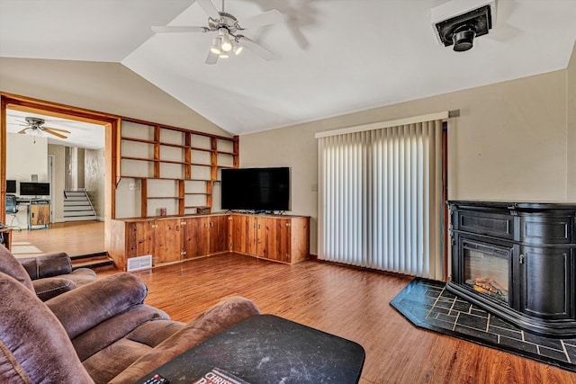 living room featuring ceiling fan, wood-type flooring, and vaulted ceiling