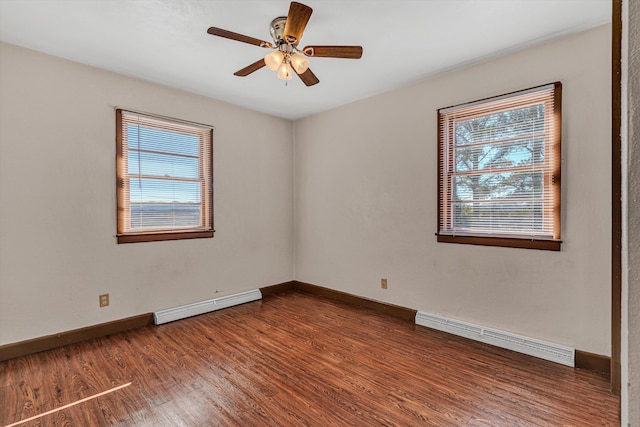 unfurnished room featuring a healthy amount of sunlight, dark hardwood / wood-style flooring, and a baseboard heating unit