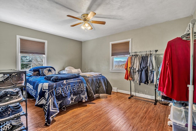 bedroom with multiple windows, hardwood / wood-style floors, and a textured ceiling