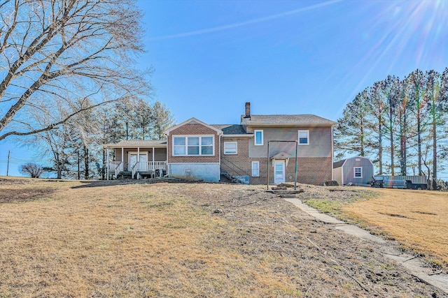 view of front of house featuring a porch, a front yard, and a storage shed