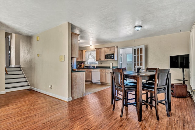 dining space with a textured ceiling and light wood-type flooring