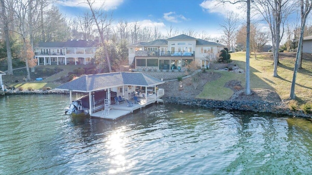 view of dock with a balcony, a water view, and a lawn