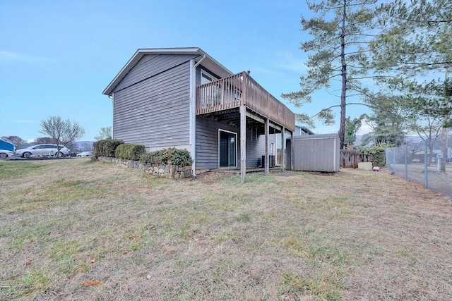 rear view of house featuring a storage shed, a lawn, and a deck