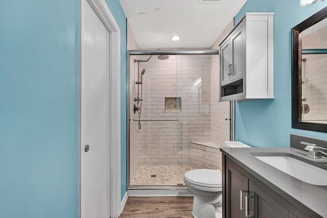 bathroom with an enclosed shower, vanity, wood-type flooring, and toilet