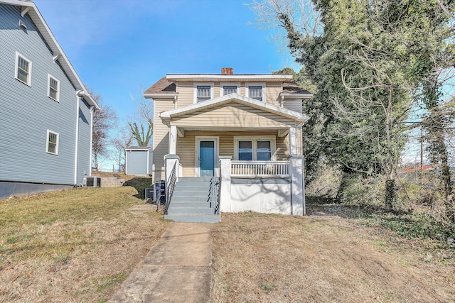 view of front of house with central AC unit, covered porch, and a front yard