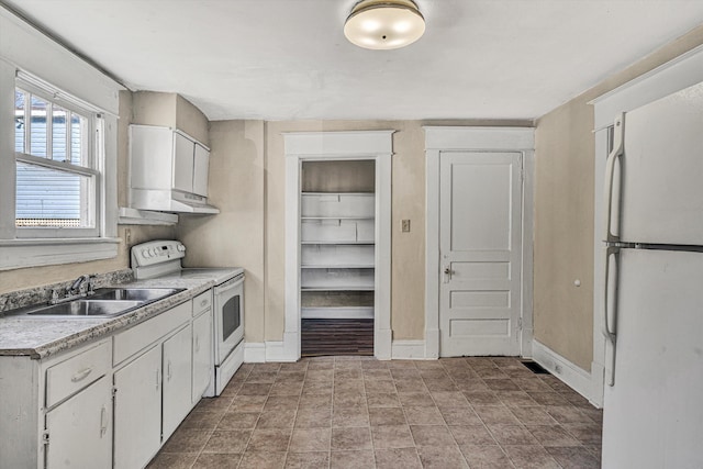 kitchen featuring white appliances, a sink, baseboards, light countertops, and white cabinetry