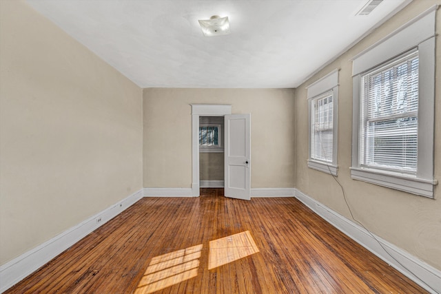 spare room featuring baseboards and hardwood / wood-style flooring
