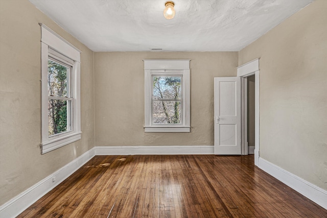 spare room with hardwood / wood-style flooring, plenty of natural light, and baseboards
