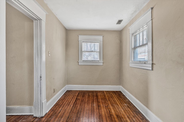 unfurnished room featuring plenty of natural light, dark wood-type flooring, and baseboards