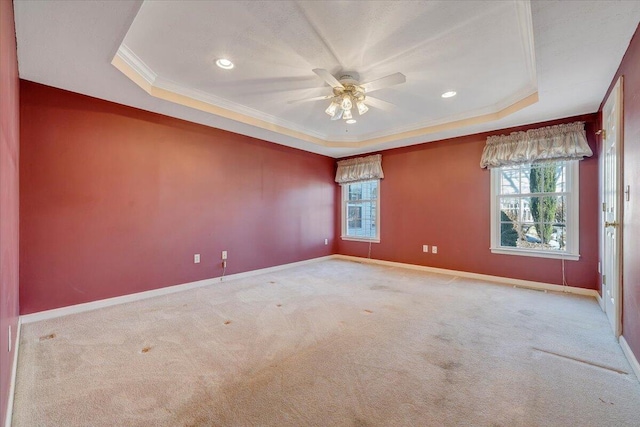 empty room featuring a raised ceiling, ornamental molding, and plenty of natural light