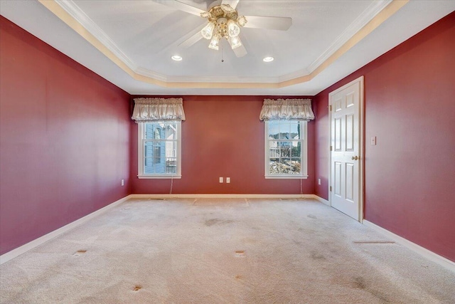 unfurnished room featuring a raised ceiling, crown molding, and light carpet