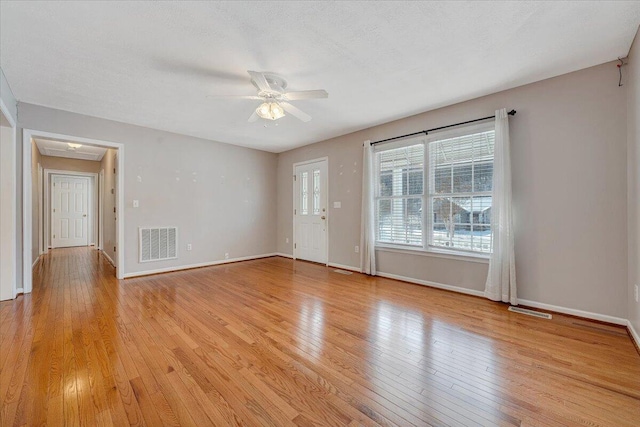 unfurnished living room with a textured ceiling, ceiling fan, and light wood-type flooring