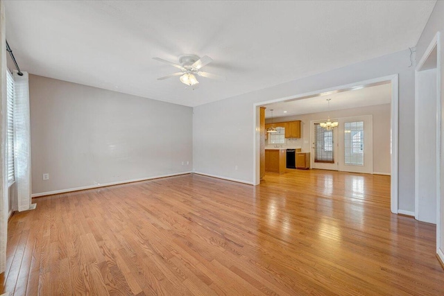 unfurnished living room featuring ceiling fan with notable chandelier and light hardwood / wood-style flooring