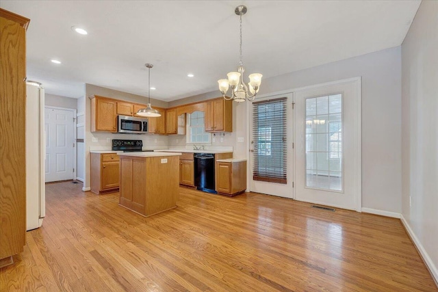 kitchen with a center island, decorative light fixtures, light wood-type flooring, and black appliances