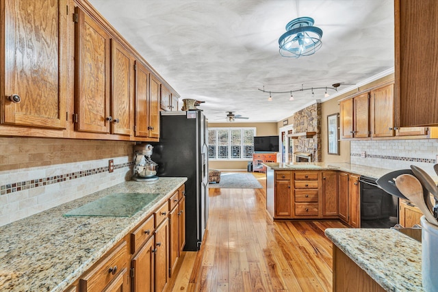 kitchen with light stone countertops, light hardwood / wood-style flooring, black appliances, and kitchen peninsula