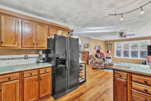 kitchen with ceiling fan, tasteful backsplash, light stone countertops, light hardwood / wood-style floors, and black fridge