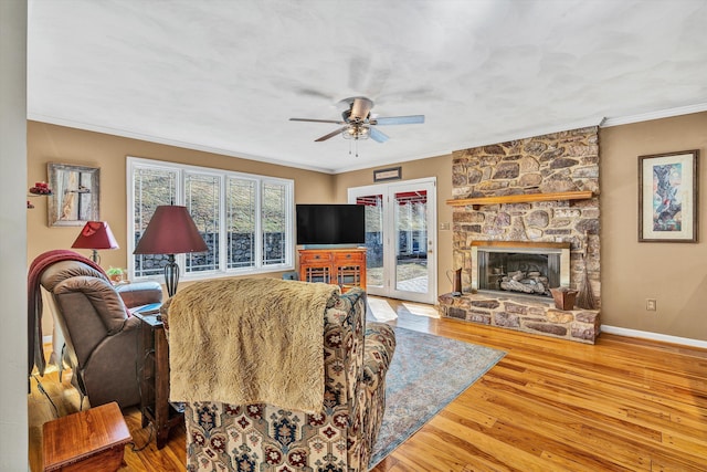 living room featuring hardwood / wood-style flooring, ornamental molding, ceiling fan, and a fireplace