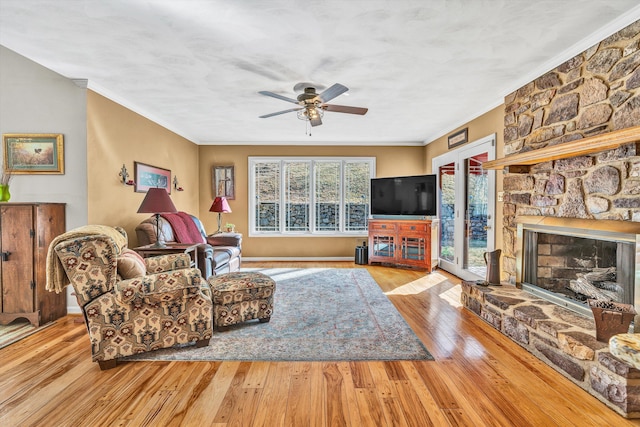 living room featuring crown molding, ceiling fan, a fireplace, and light hardwood / wood-style floors