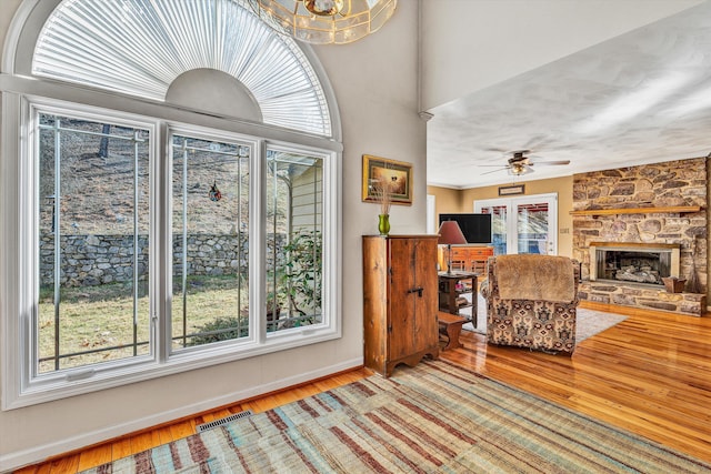 interior space with a stone fireplace, plenty of natural light, and hardwood / wood-style floors