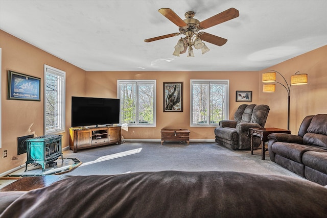 carpeted living room with ceiling fan and a wood stove