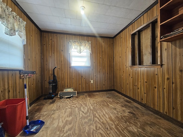 unfurnished room featuring ornamental molding, hardwood / wood-style floors, and wood walls