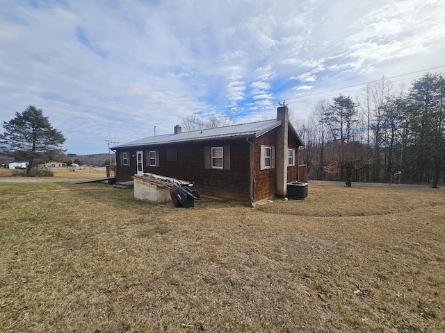 view of side of property featuring cooling unit and a yard