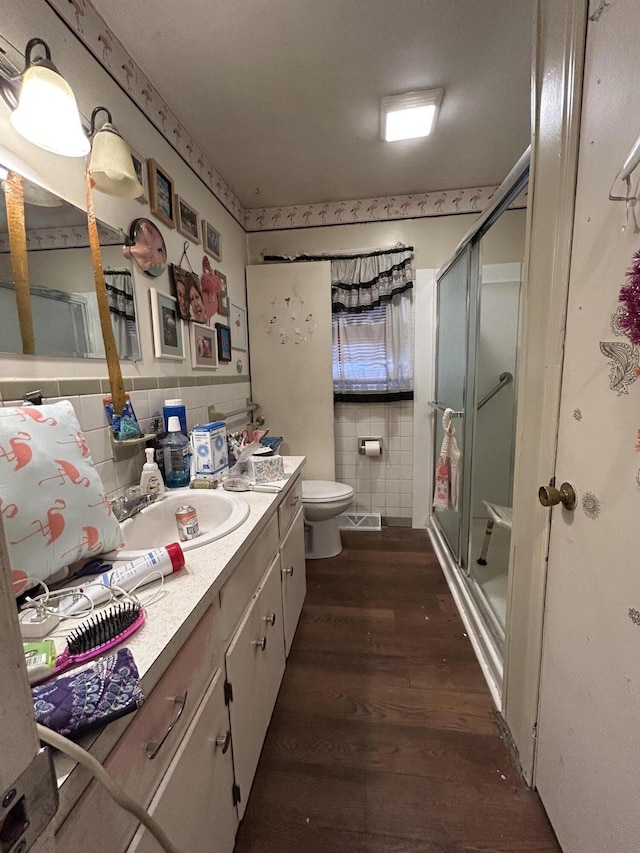 bathroom featuring toilet, tile walls, vanity, a shower with door, and hardwood / wood-style flooring