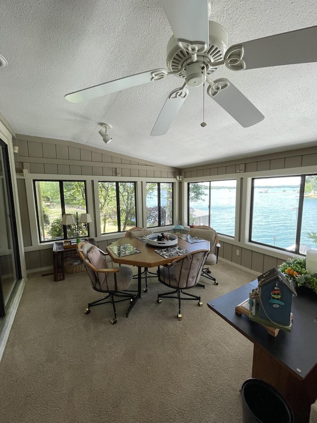 unfurnished sunroom featuring a water view, lofted ceiling, and ceiling fan