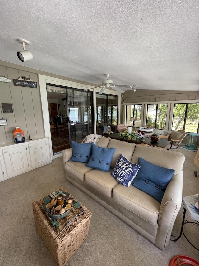 carpeted living room with lofted ceiling, a textured ceiling, and ceiling fan