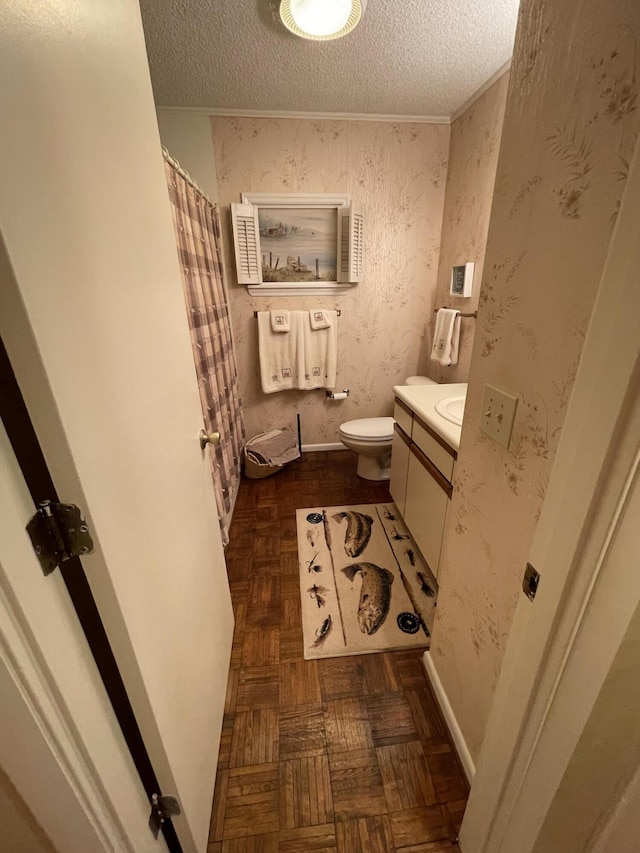 bathroom with parquet floors, vanity, toilet, and a textured ceiling