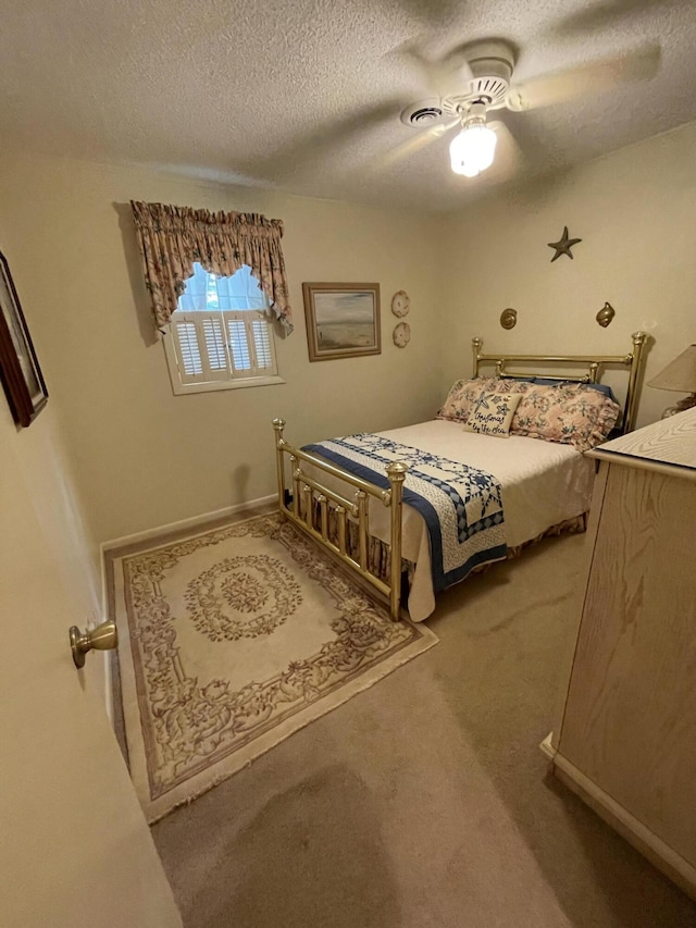 carpeted bedroom featuring ceiling fan and a textured ceiling